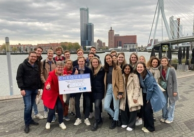 Lisbeth Utens en de Young Unilver Managers staan in Rotterdam voor de Erasmusbrug met een checque van 5000 euro